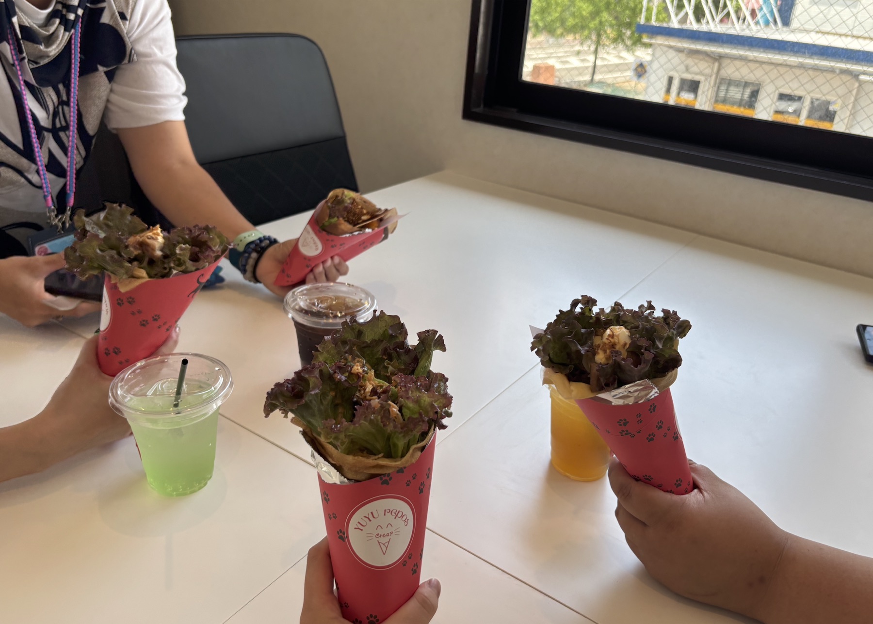 事業所の机を囲み、クレープと飲み物を並べて過ごす様子
