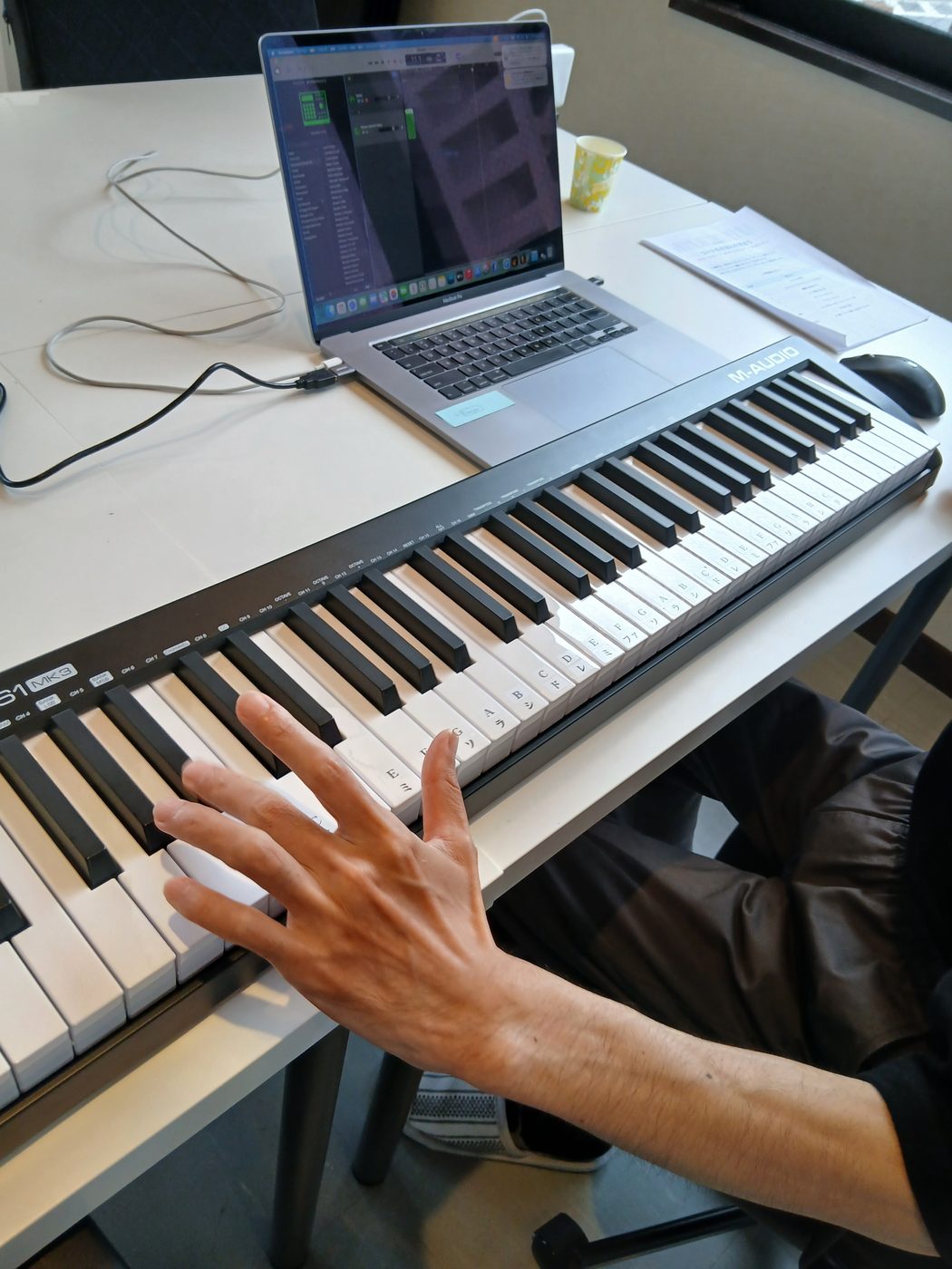 MIDIキーボードとノートパソコンのDAWを使って、午後の音楽制作に取り組む利用者様の手元