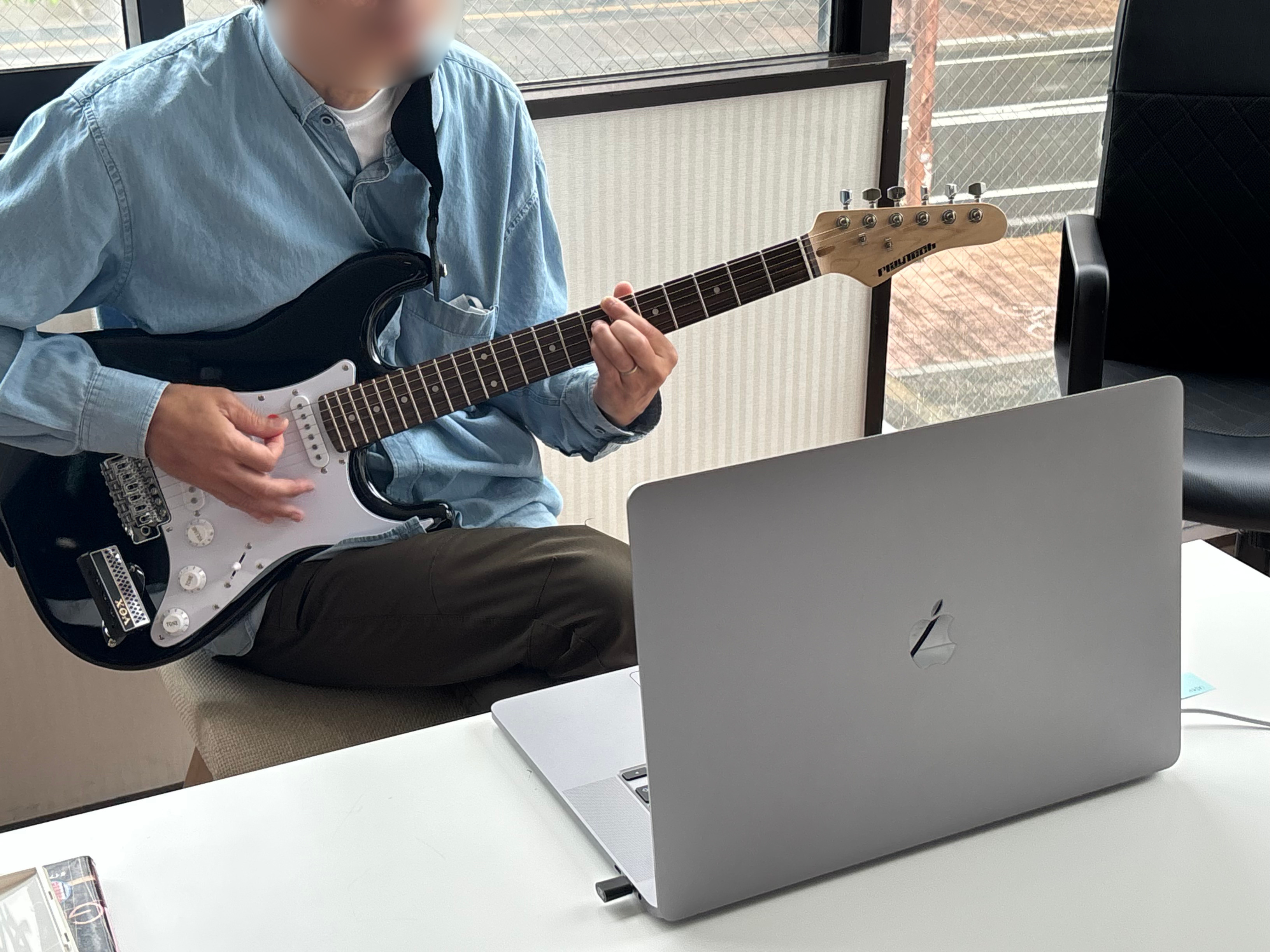 MacBookを見ながらギターのオンラインレッスンを受ける様子