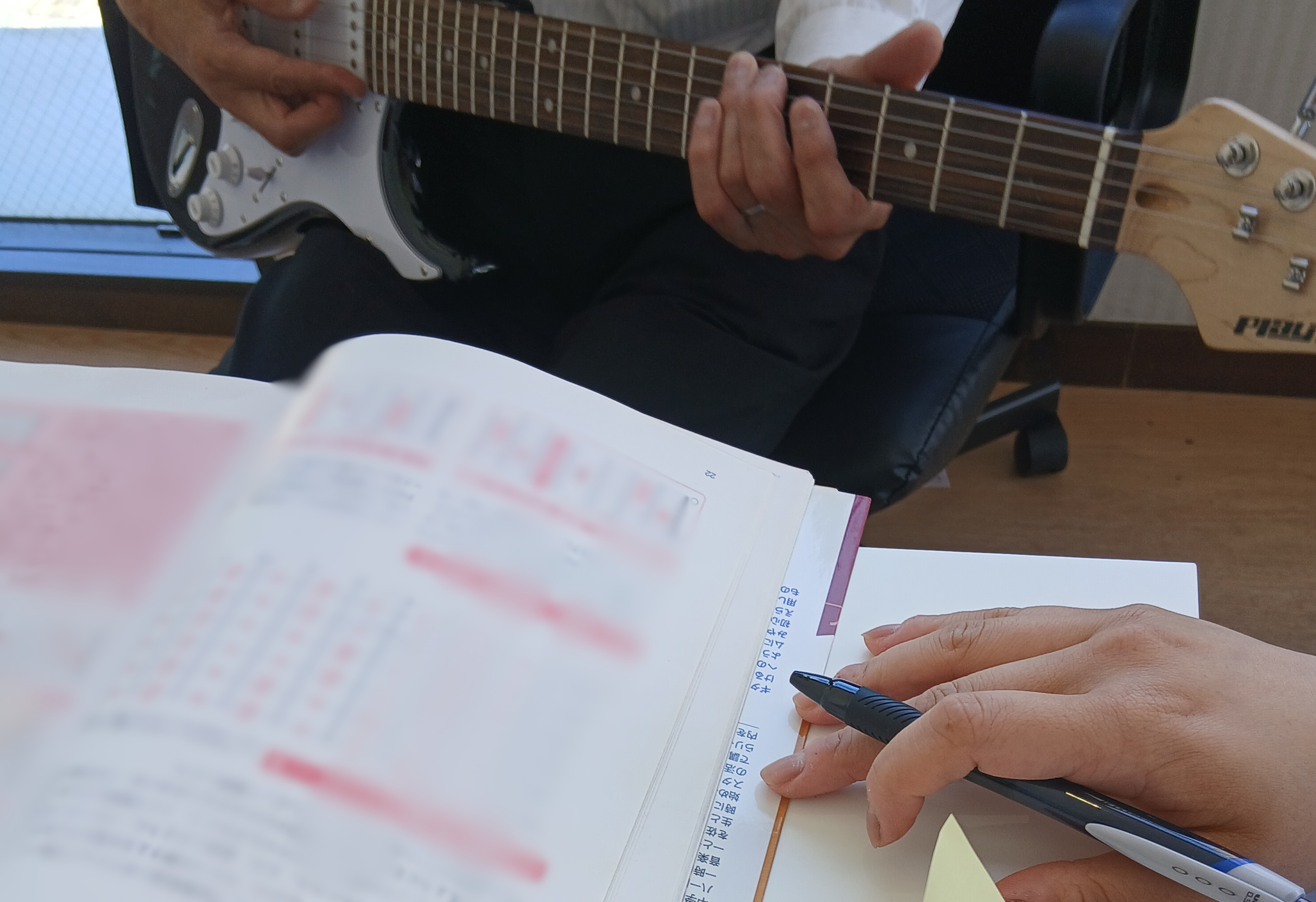 ギターを弾きながら音楽理論のテキストで練習するALOHAの利用者様